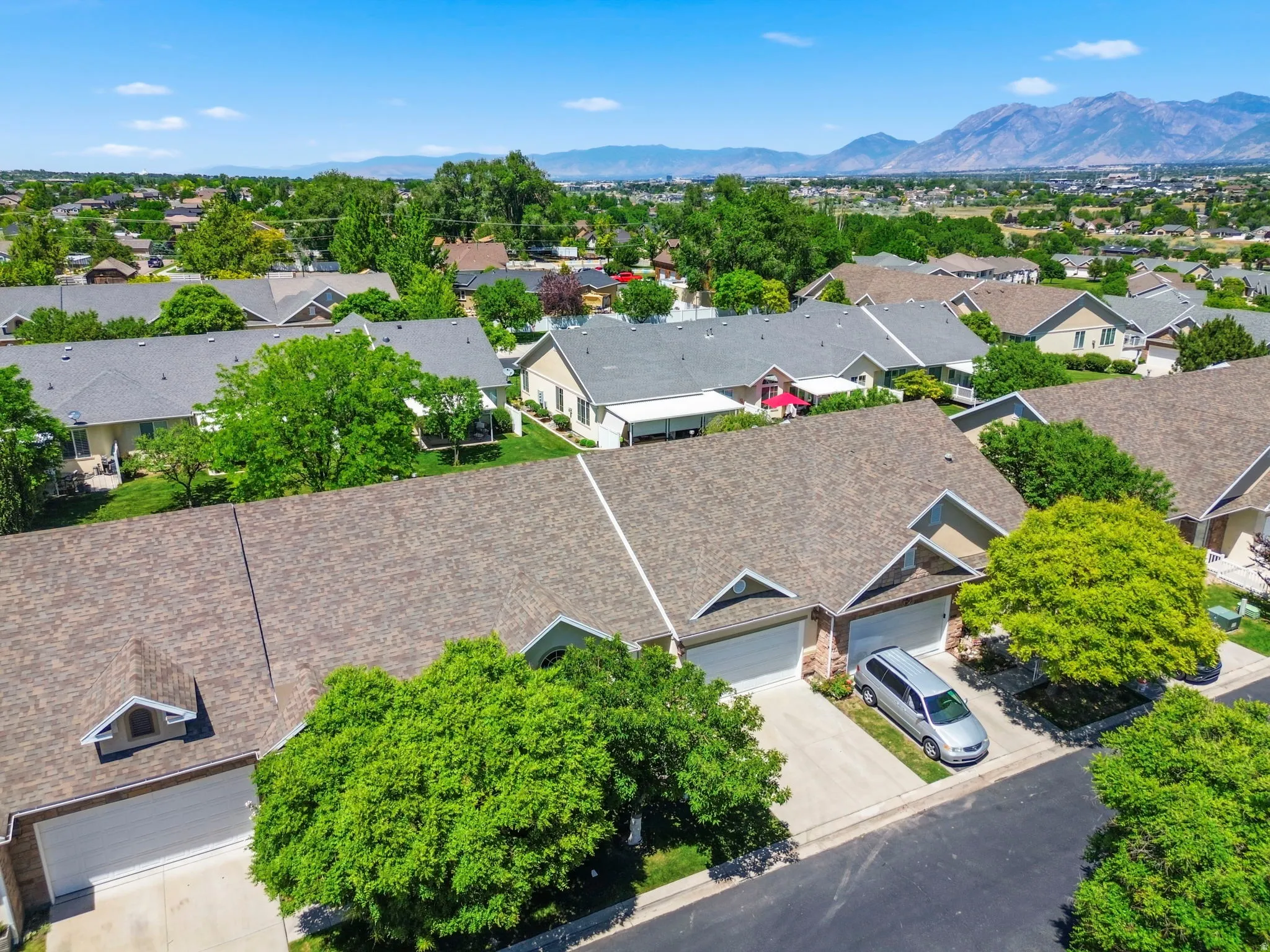 Aerial perspective showcasing residential properties with brown shingle roofing and attached garages