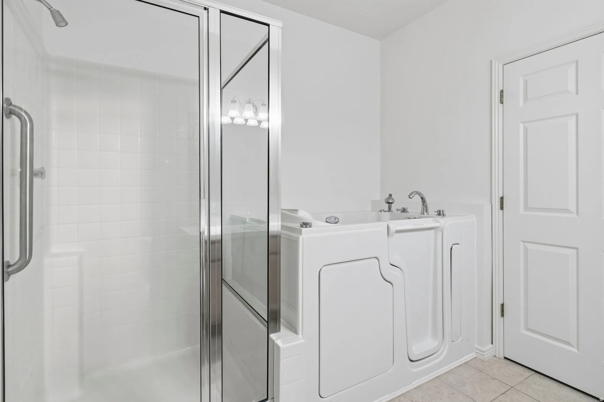 Master en suite bathroom featuring a walk-in tub and a separate shower with a grab bar