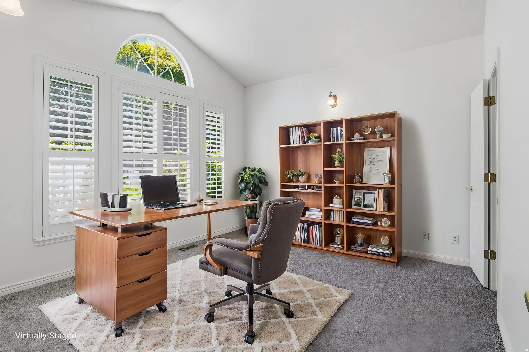 Vaulted ceilings feature an arched window above a bank of three windows with white plantation shutters