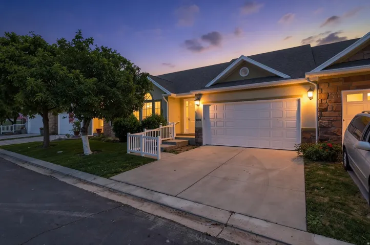 Exterior facade featuring a two-car garage, concrete driveway, and a welcoming entry with a white railing