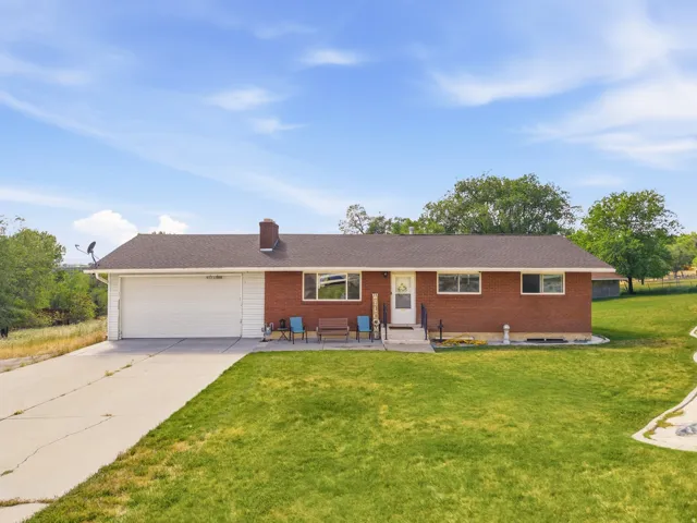 Brick ranch-style residence featuring a two-car garage, concrete driveway, and front lawn