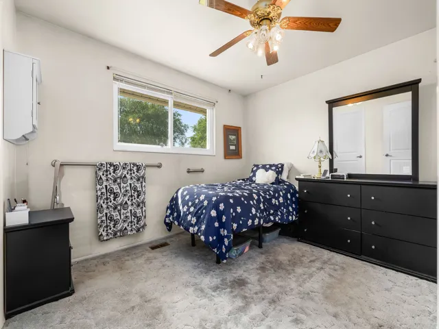 Room featuring a window, built-in ceiling fan with lighting, wall-to-wall carpeting, and light-toned wall finishes