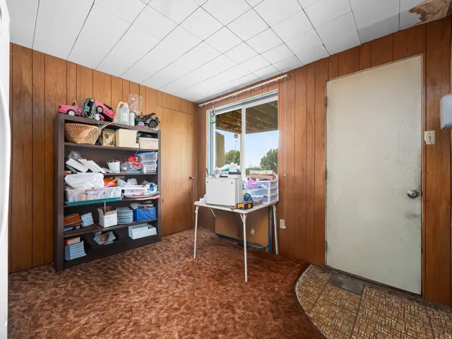 Room featuring wood-paneled walls, a drop ceiling, and patterned carpet flooring