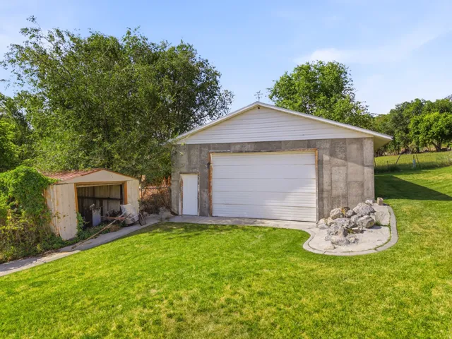 Detached concrete block garage with a white sectional door and a separate entry door