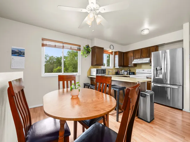 Open-concept kitchen and dining area featuring wood-finish flooring, a ceiling fan, and ample natural light