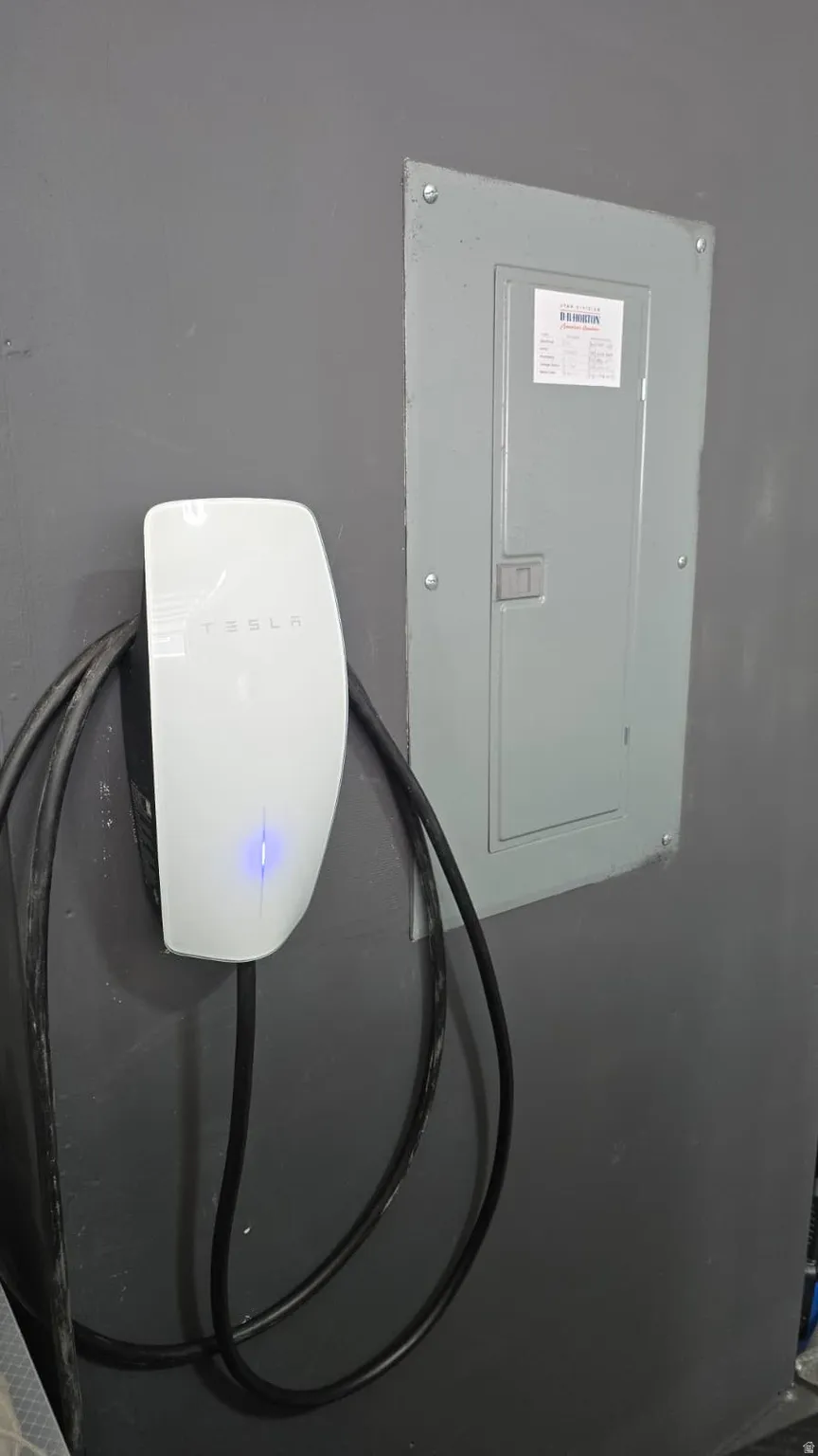Electric vehicle charging station with integrated cable management and nearby electrical panel