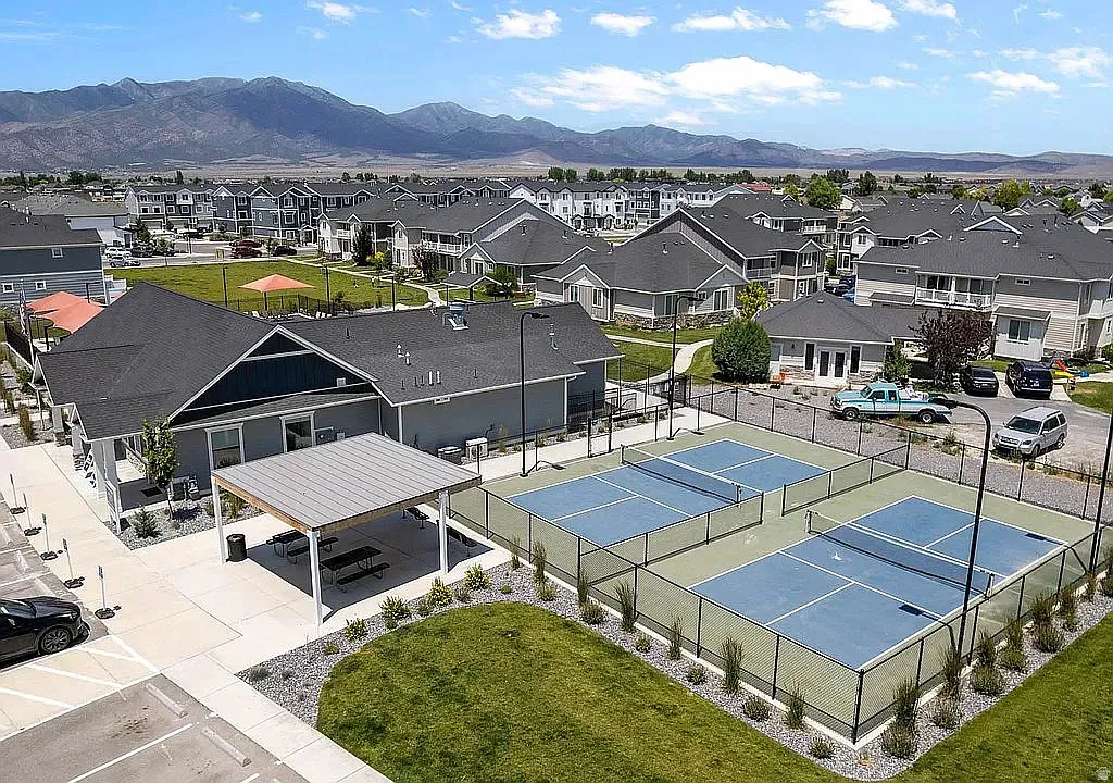 Community amenities featuring multiple pickleball courts, a covered outdoor dining area, and a large central green space
