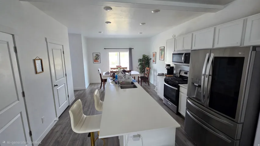Modern kitchen featuring a large center island with integrated sink, stainless steel appliances, white cabinetry, and recessed lighting
