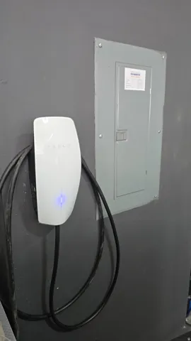 Electric vehicle charging station with integrated cable management and nearby electrical panel