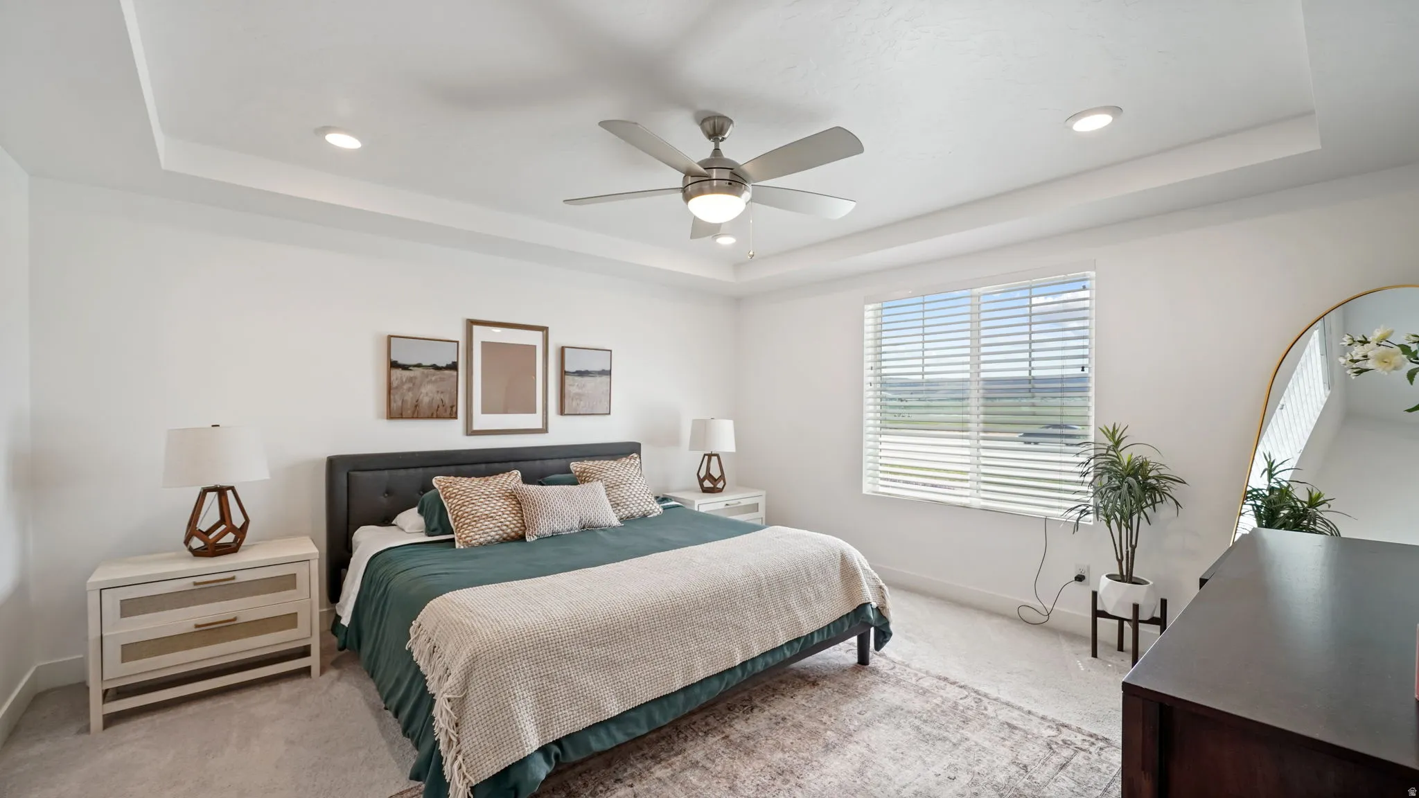 Spacious bedroom featuring a tray ceiling, recessed lighting, ceiling fan, and large window with blinds