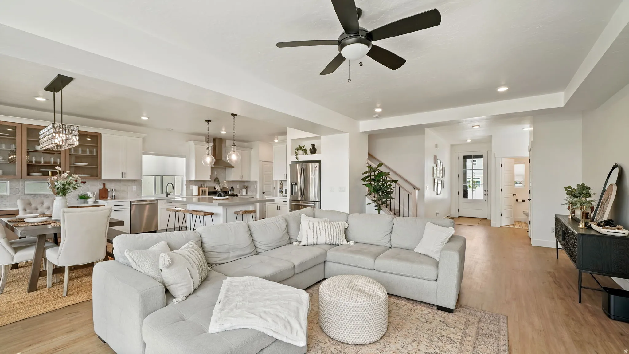 Spacious open-concept living area featuring wood-finish flooring and a contemporary ceiling fan