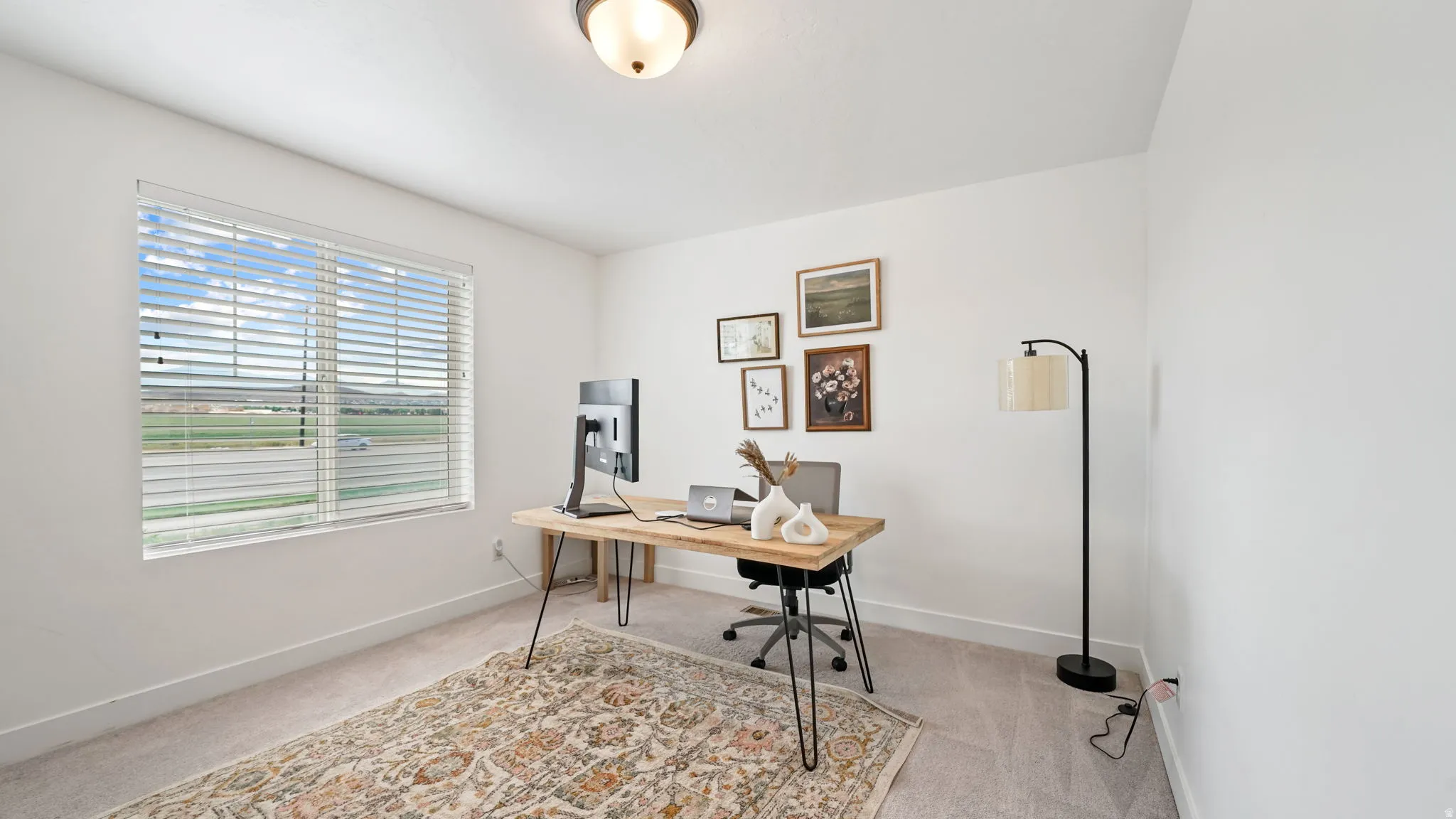 Room featuring a large window with blinds, light-colored carpeting, white walls, and a semi-flush ceiling light fixture