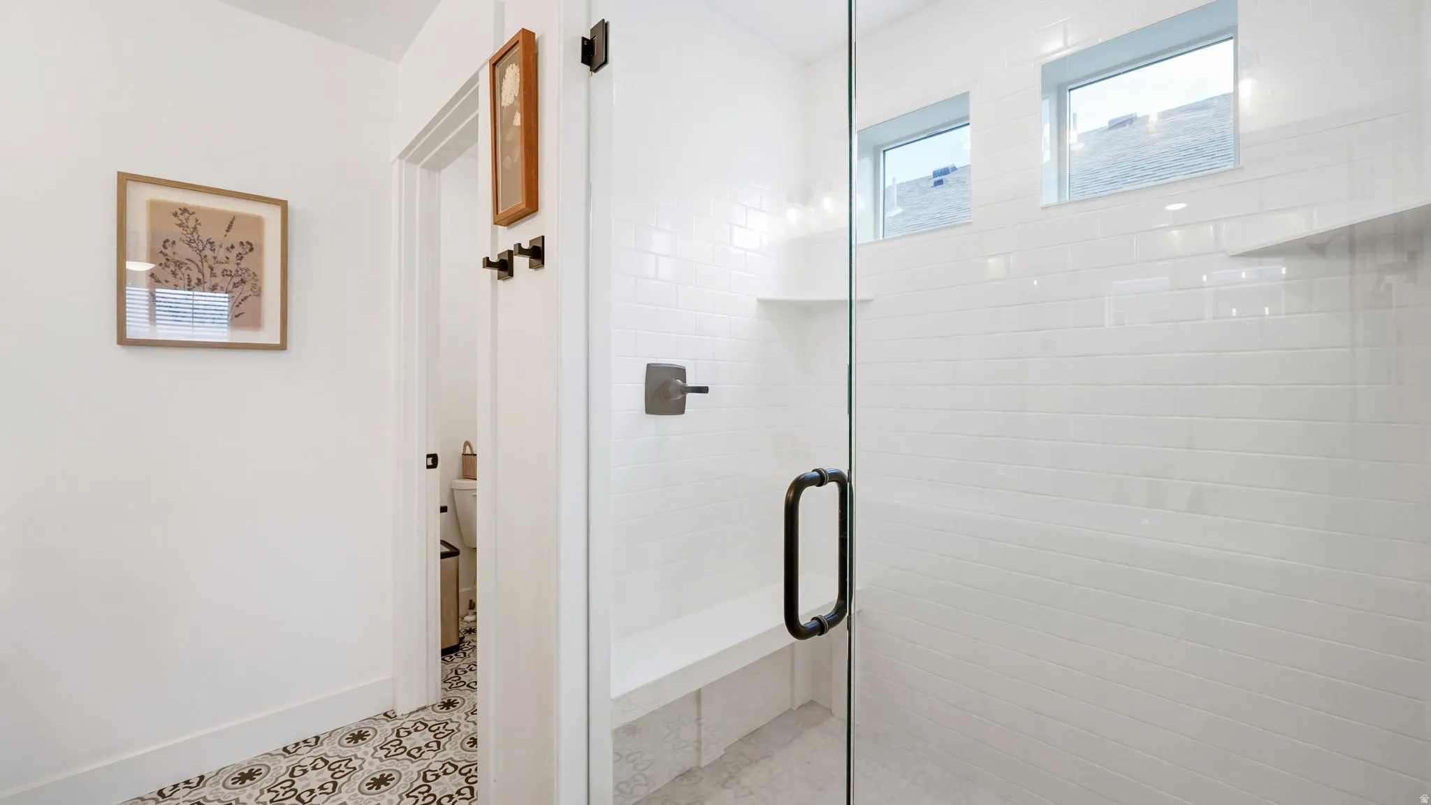 Glass-enclosed shower featuring subway tile, an integrated bench, and matte black hardware