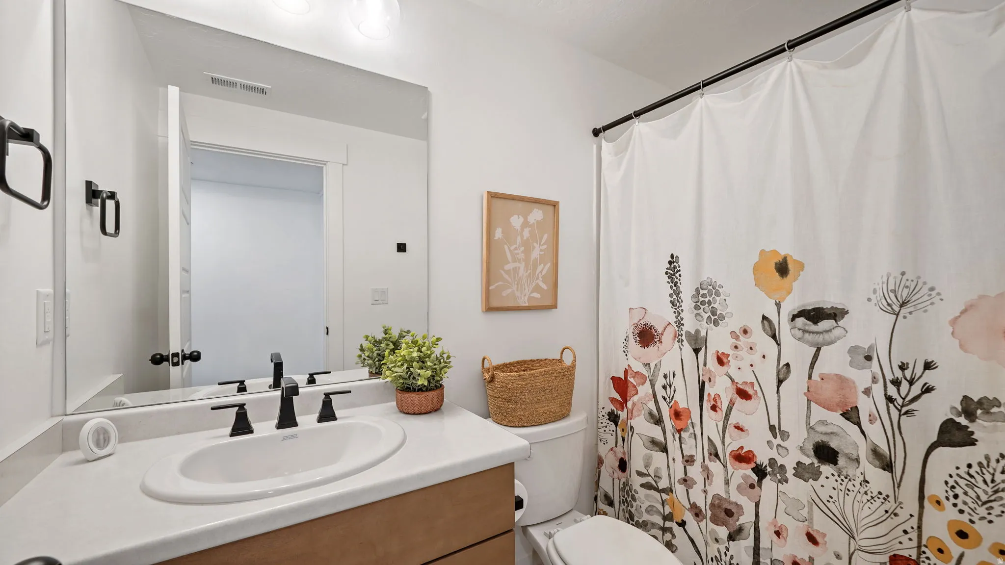 Bathroom featuring a vanity with a white countertop and undermount sink, matte black faucet, and a large wall-mounted mirror