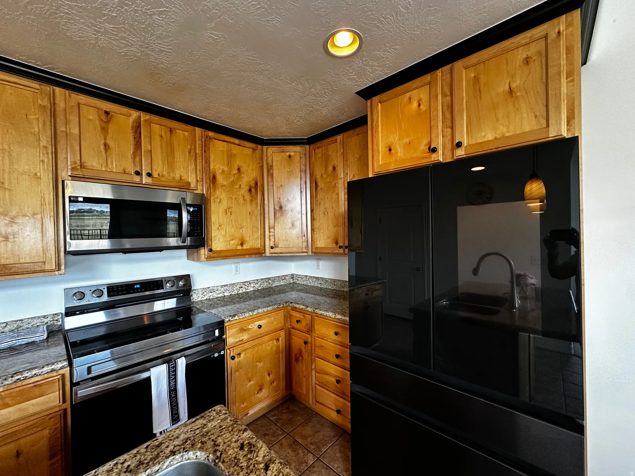Kitchen featuring natural wood cabinetry with black hardware and crown molding