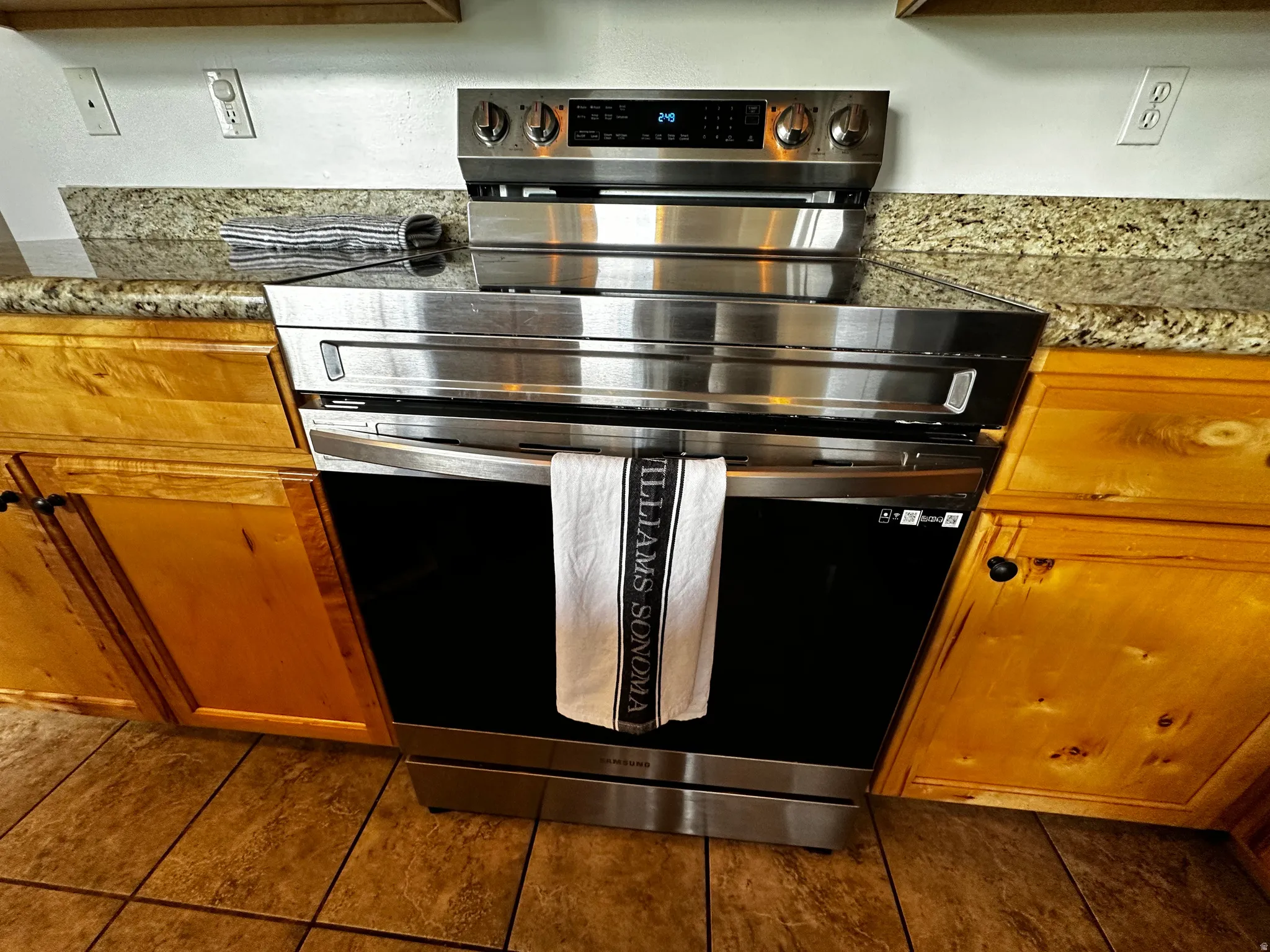 Stainless steel range with a smooth cooktop surface, integrated into a countertop with a stone-finish
