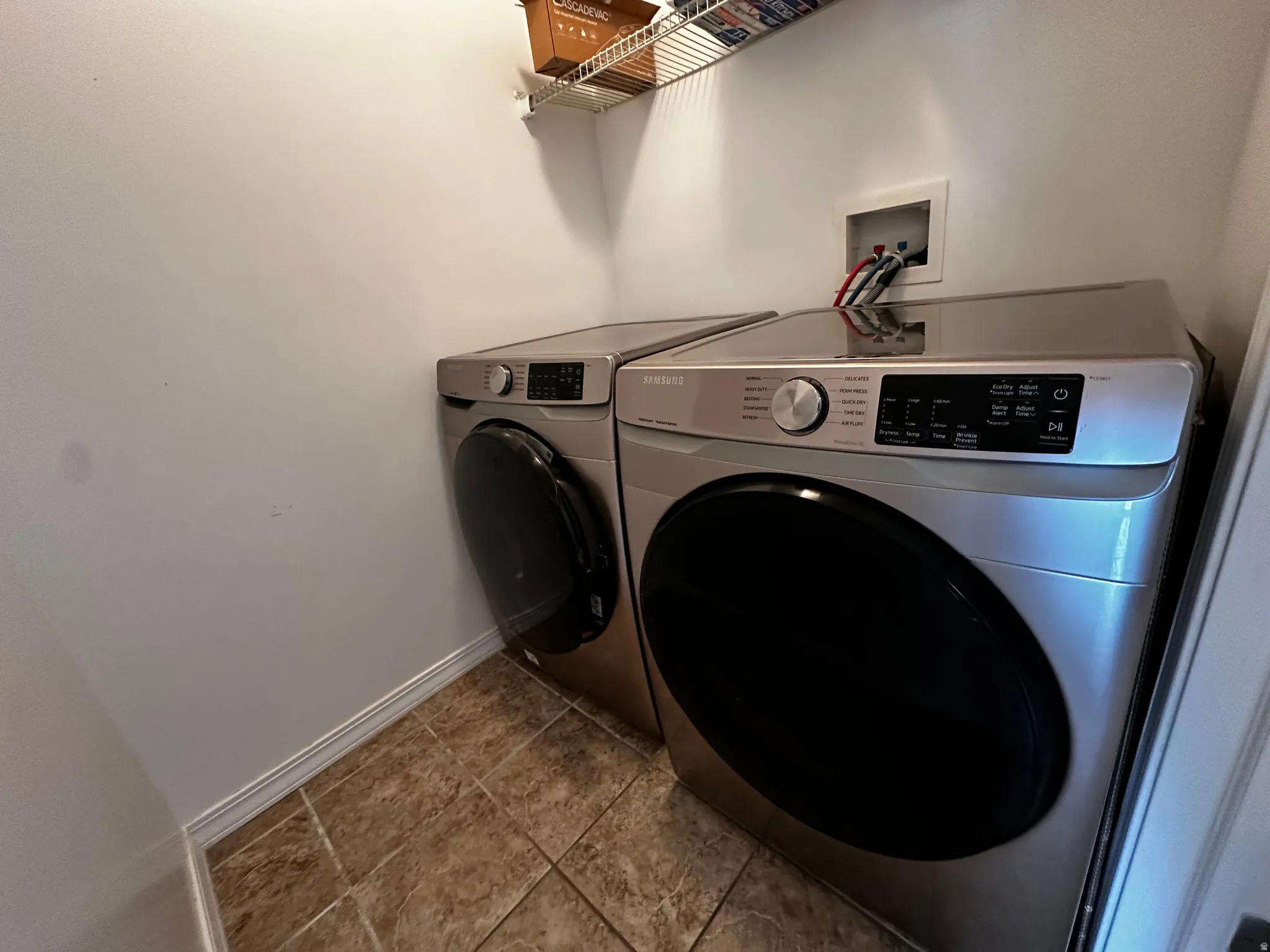 Dedicated laundry area featuring tile flooring and a wire storage shelf