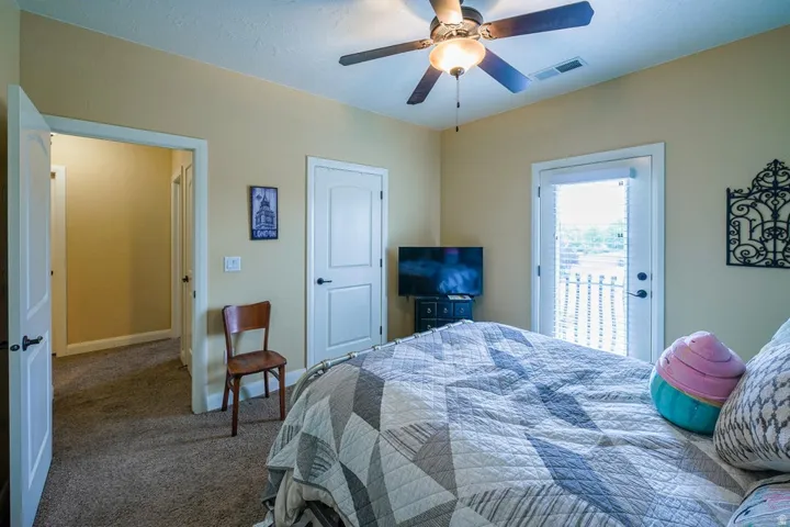 Carpeted room featuring a ceiling fan with light fixture, light beige wall paint, white trim, and a white door with a black handle