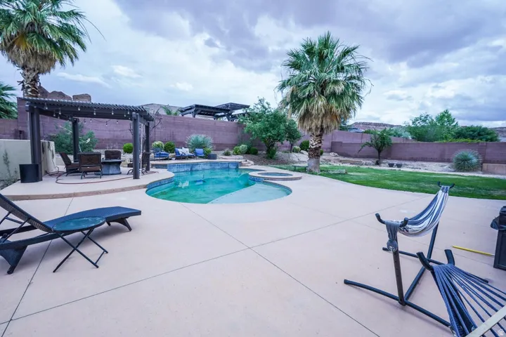 Curved swimming pool with an integrated spa, surrounded by expansive concrete decking