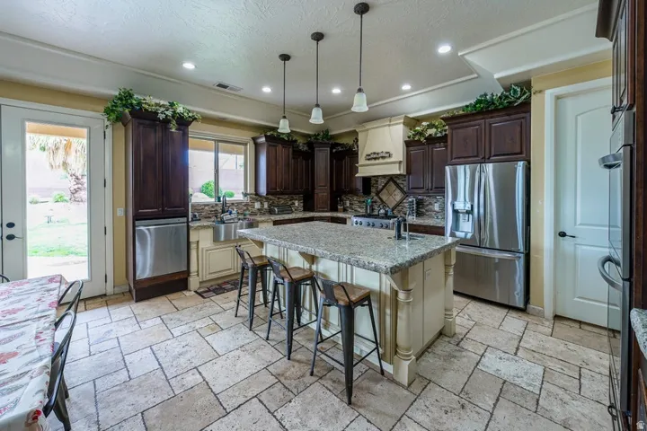 Kitchen featuring an expansive center island with seating, a dual-basin undermount sink, and stainless steel appliances