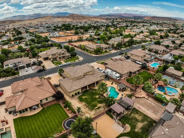 Expansive aerial view of a residential neighborhood featuring multiple properties with private swimming pools, covered patios, and mature landscaping