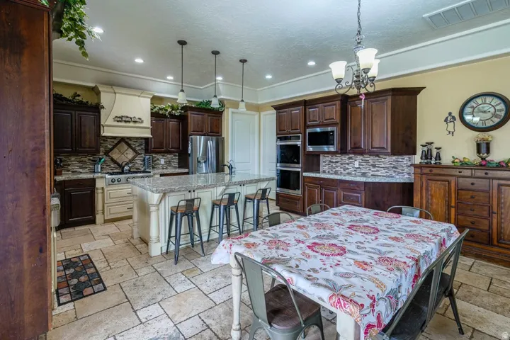 Kitchen featuring a center island with bar seating, dual-tone cabinetry, stone tile flooring, stainless steel appliances, and a tiled backsplash