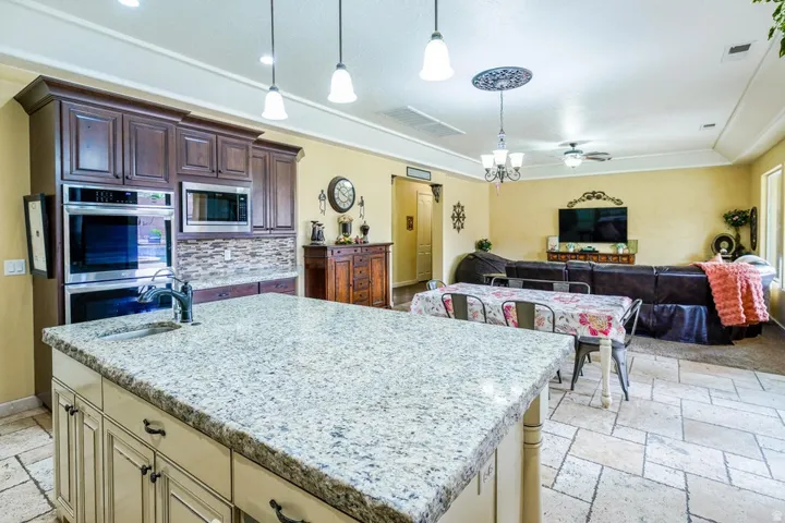 Kitchen island featuring a light-toned granite countertop with an undermount sink and a gooseneck faucet