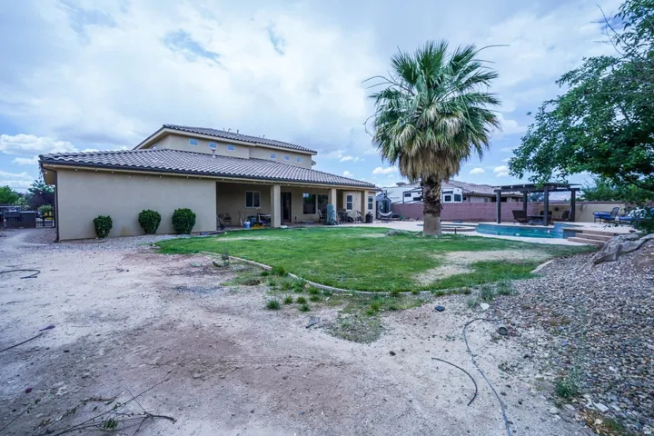 Rear exterior featuring a tiled roof, covered patio, manicured lawn, and a swimming pool with an adjacent pergola