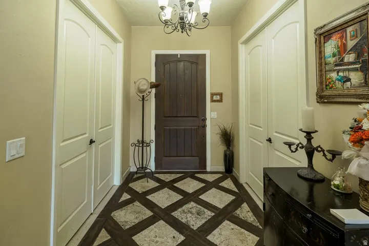 Entryway featuring patterned tile flooring, a dark wood-paneled door, and a decorative chandelier