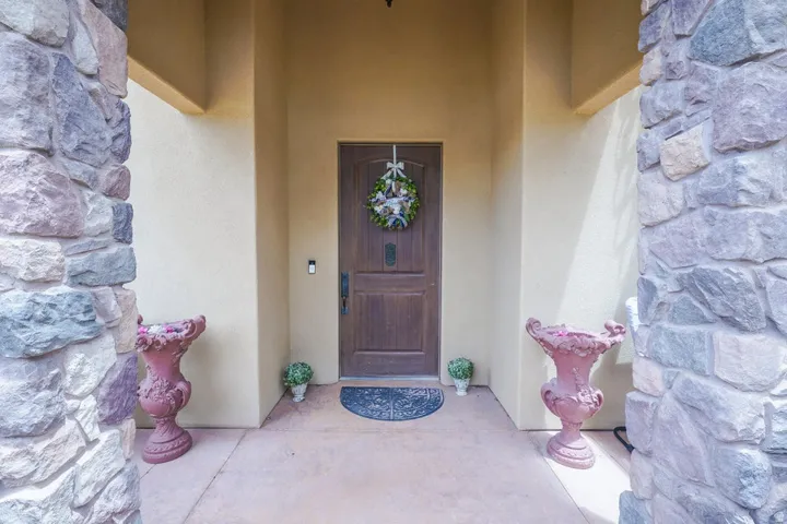 Entryway with stacked stone columns, stucco exterior, and a paneled wood-finish door