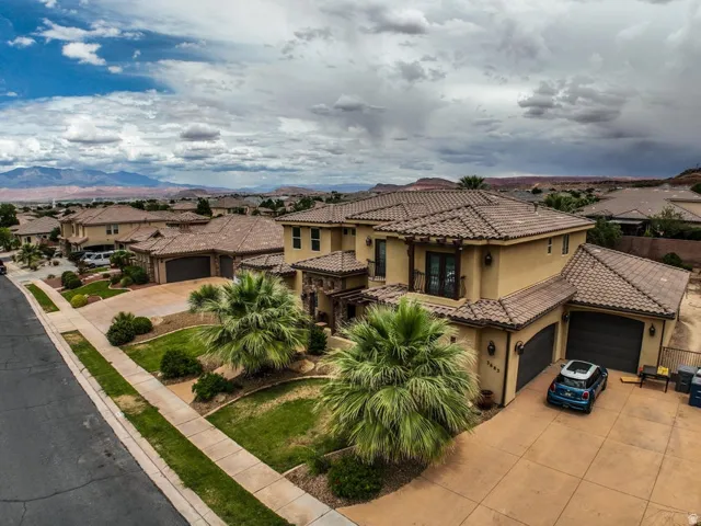 Mediterranean-inspired residence featuring a stucco exterior, tile roofing, and multiple garage doors