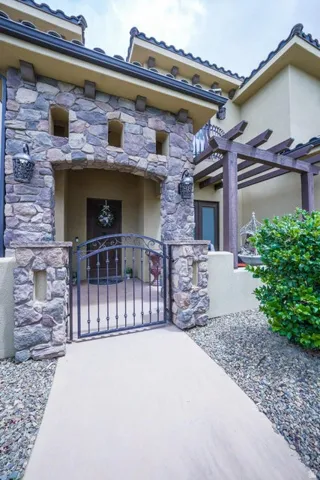 Stone facade entry with arched portico, wrought iron gate, and decorative exterior lighting fixtures