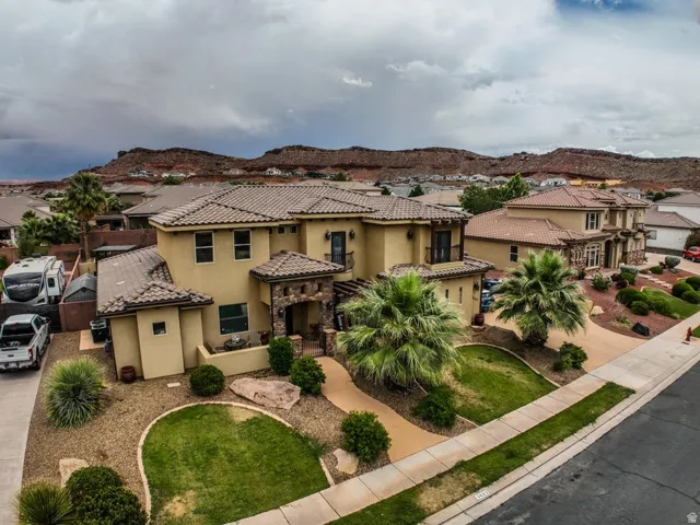 Stucco exterior home with stone accents, featuring a tiled roof and a paved driveway