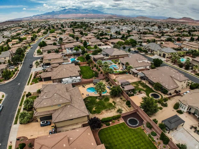 Residential neighborhood featuring a series of single-family homes with tile roofs, private swimming pools, and landscaped backyards