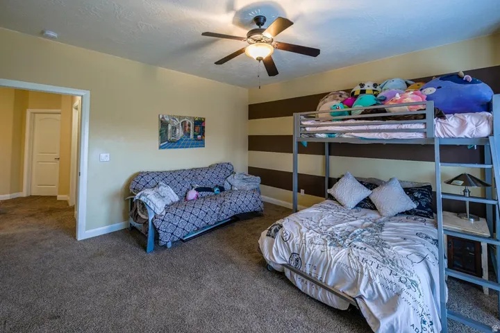 Spacious room featuring neutral carpeting, a ceiling fan with integrated lighting, and a doorway with white trim