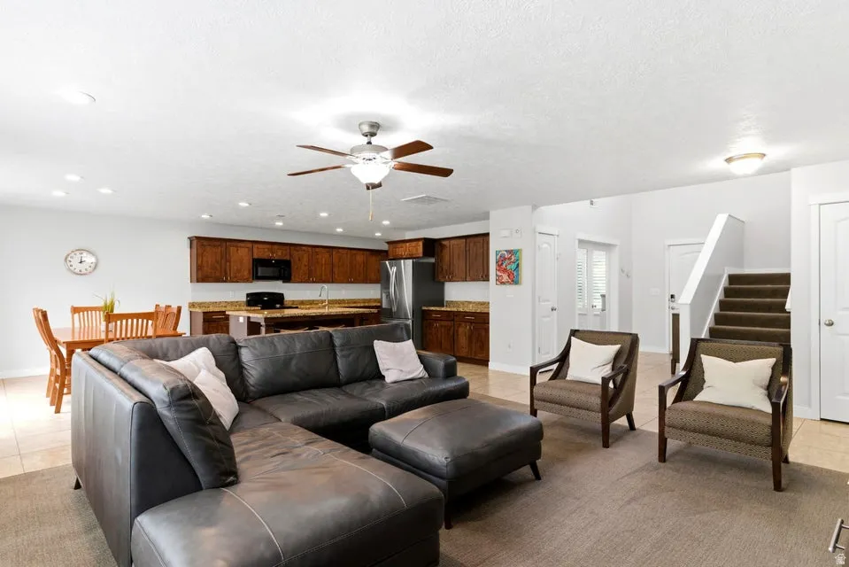 Open-concept living space featuring a ceiling fan, recessed lighting, and a neutral color palette