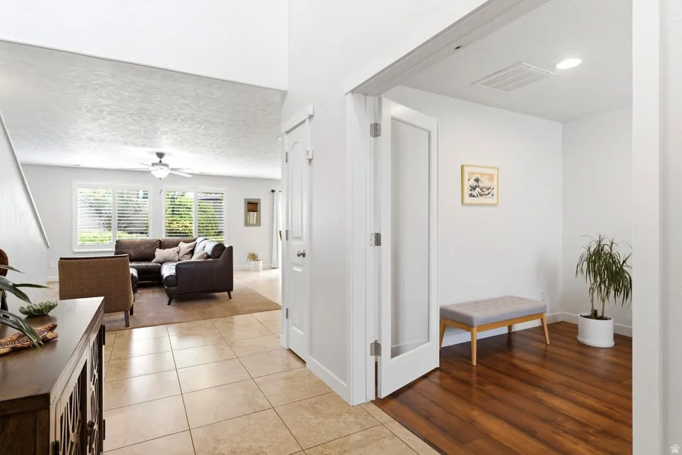 Open concept living area with tiled flooring, white walls, and a ceiling fan