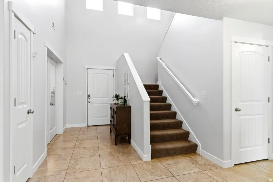 Entryway featuring a staircase with carpeted treads and a white railing, tile flooring, and multiple white paneled doors