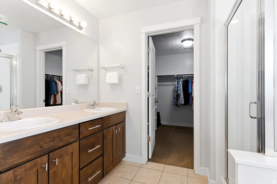 Bathroom featuring a double vanity with wood cabinetry, light-toned countertop, and two undermount sinks