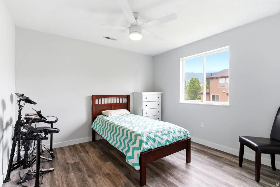 Bedroom with wood-finish flooring, white walls, and a window framing distant mountains