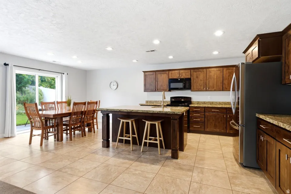 Spacious kitchen featuring warm wood cabinetry, granite countertops, and stainless steel appliances