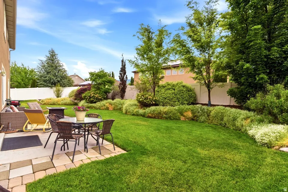 Expansive backyard featuring a manicured lawn, established landscaping, and a paver patio