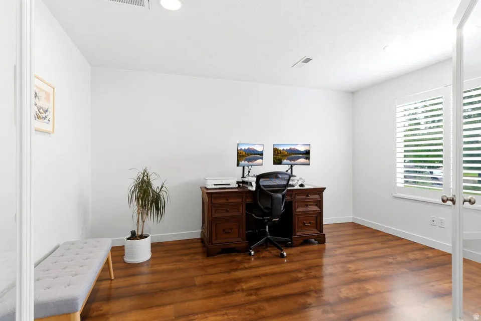 Spacious room featuring wood-finish flooring, white walls, and bright overhead lighting