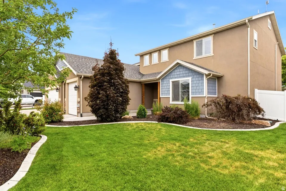 Stucco exterior featuring light blue shingle accents and a white privacy fence
