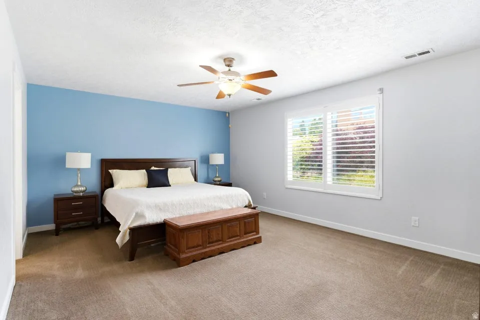 Carpeted bedroom with a window featuring white plantation shutters