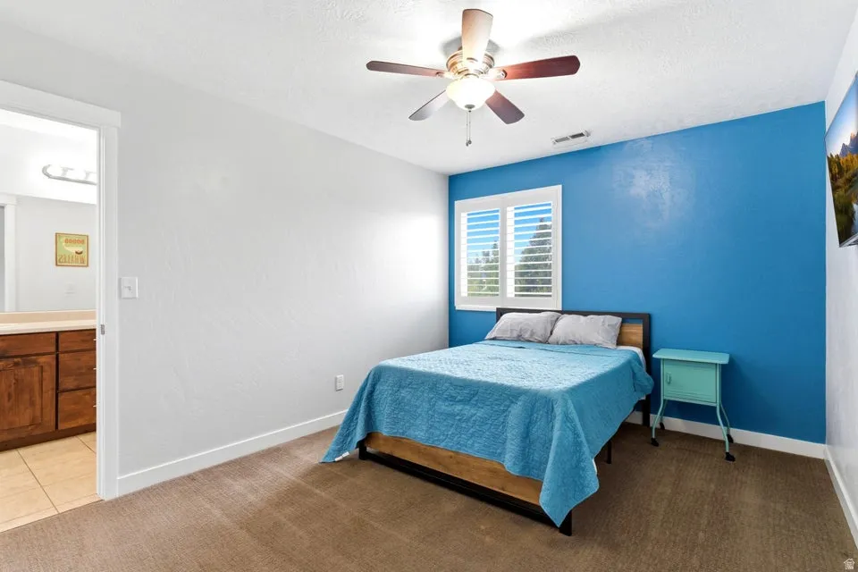 Bedroom featuring a blue accent wall, neutral carpet flooring, and a ceiling fan with integrated lighting