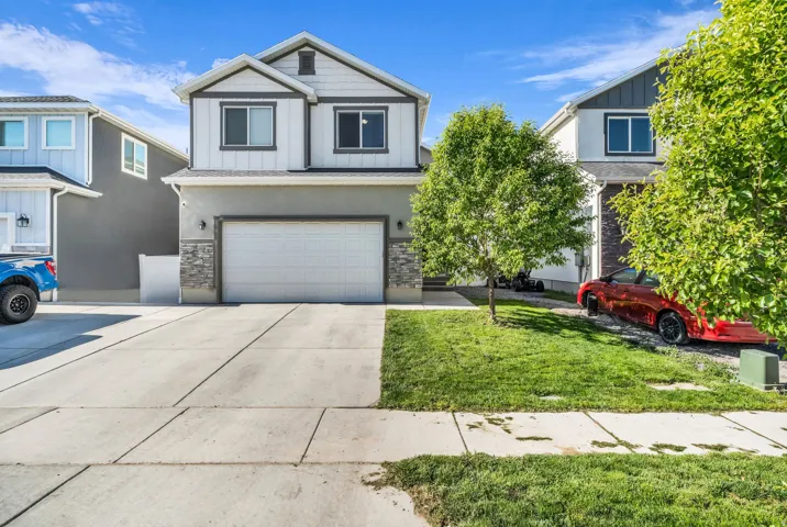 Two-story residence featuring a two-car garage with a white overhead door, a concrete driveway, and a manicured front lawn