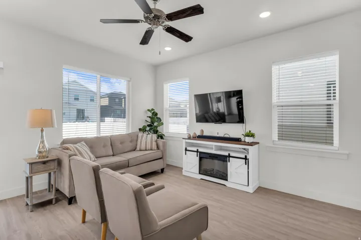 Spacious living area featuring large windows, light wood-finish flooring, recessed lighting, a ceiling fan,
