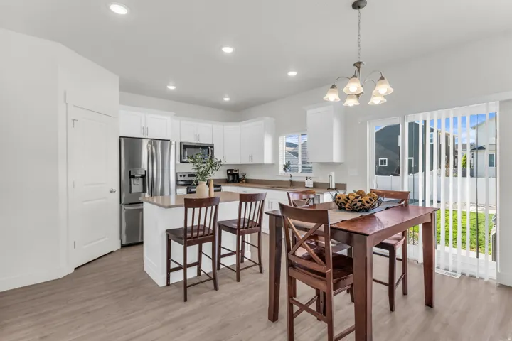 Contemporary kitchen and dining area featuring white cabinetry, stainless steel appliances, and a central island with countertop seating