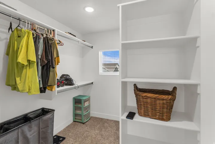 Primary Walk-in closet featuring built-in shelving, hanging rods, recessed lighting,